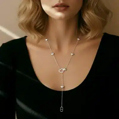 Du trägst ein schwarzes Top und setzt mit der Full Love Kette, verziert mit Herzanhängern und Schloss, ein modernes Statement.