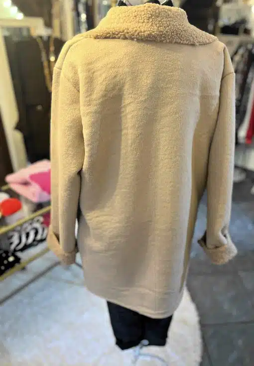 Entdecke deinen neuen Look: Ein tanfarbener Fleece-Mantel mit lässig umgeschlagenen Ärmeln wartet in der Boutique auf dich.