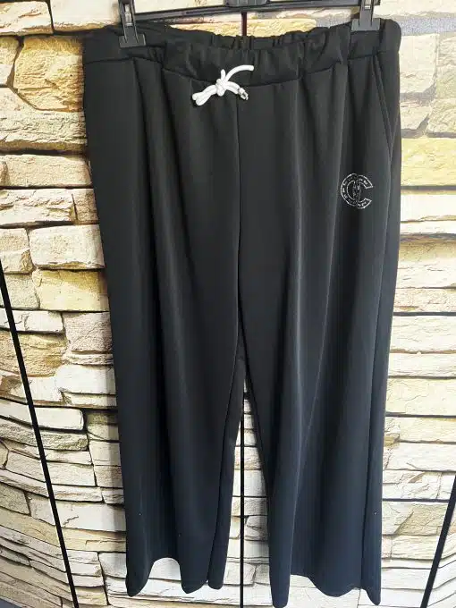 Hol dir die schwarzen Glam Lounge Strass Pants mit weißem Logo - stylisch vor Steinmuster. Dein Style-Upgrade wartet!.