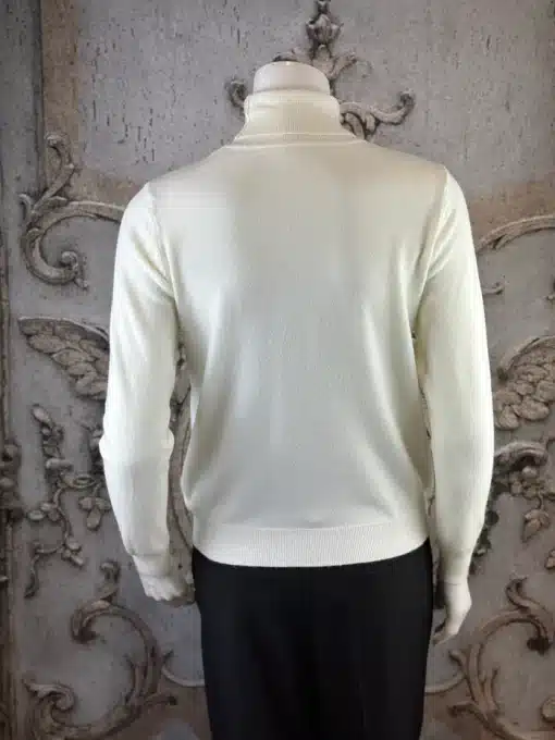 Zeige deinen Style: Im Sparkle Line Turtleneck und schwarzen Pants stichst du vor einer edlen Wandkulisse modern hervor.