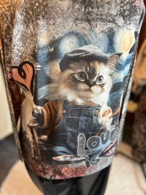 Erlebe den coolen Look: Ein Kätzchen in Latzhose und Cap mit Pinsel - dein Statement "love is" auf dem Pullover.