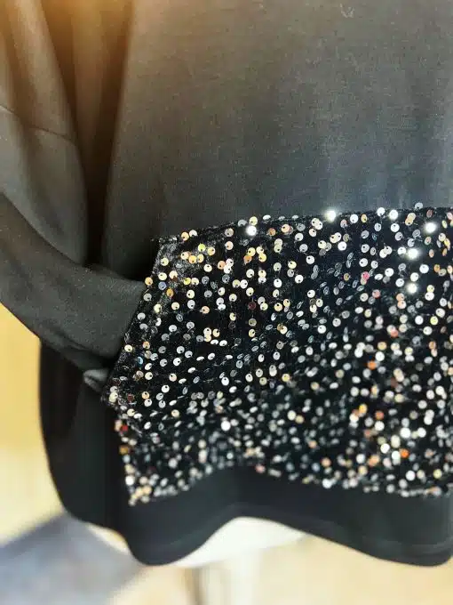 Erlebe dein Statement: Schwarzes Oversize-Shirt mit großer Tasche, trendigen Pailletten-Schleifen und atemberaubendem Glanz.