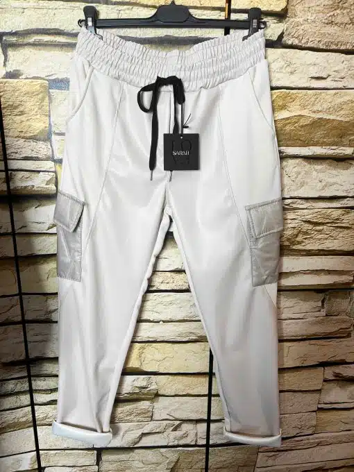 Entdecke deine neue Cargo-Jogpants in moderner Lederoptik mit stylischen Taschen und schwarzem Kordelzug vor Steinwand.