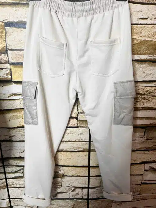 Entdecke deine neue Cargo-Jogpants in angesagter Lederoptik mit grauen Taschen und coolen Turn-ups - lässig vor Steinwand.