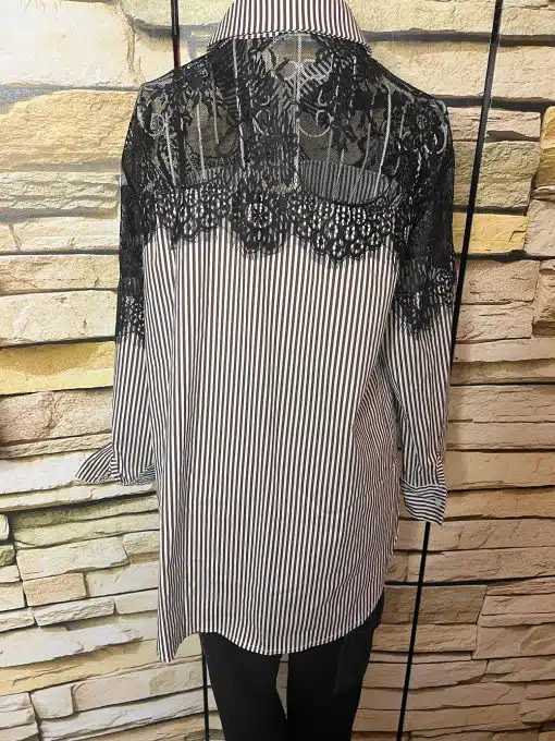 Entdecke deinen Style: Ein cooles Streifenshirt mit schwarzen Spitzen-Details an den Schultern vor trendiger Steinwand.