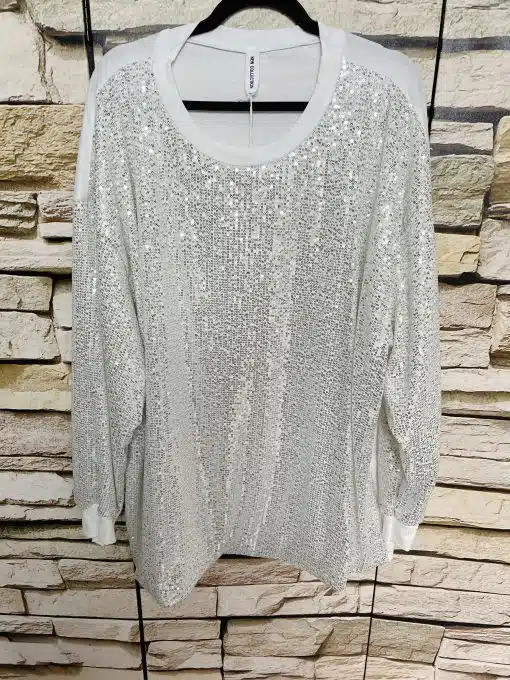 Hol dir den Wow-Faktor: Das Glam Sequin Oversize Shirt in Weiß mit Glitzerpailletten wartet stylish auf dich vor Steinwand!.