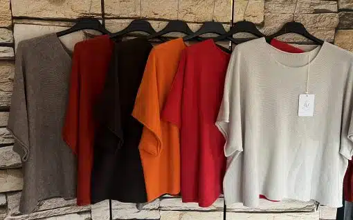 Entdecke deinen Look: Sechs Soft Touch Pullover in Grau, Rot, Braun, Orange und Beige - stylish präsentiert auf schwarzen Bügeln.