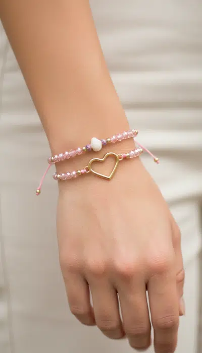 Trage die Zwillingsherz Love Bracelet Twins: Zwei pinke Armbänder, eines mit Herzanhänger, das andere mit weißer Perle.