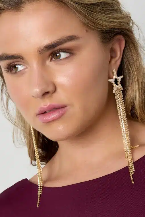 Du strahlst pure Eleganz aus: Im Burgundy-Top, mit welligem Haar und funkelnden Luxus Star Ohrsteckern aus Gold.