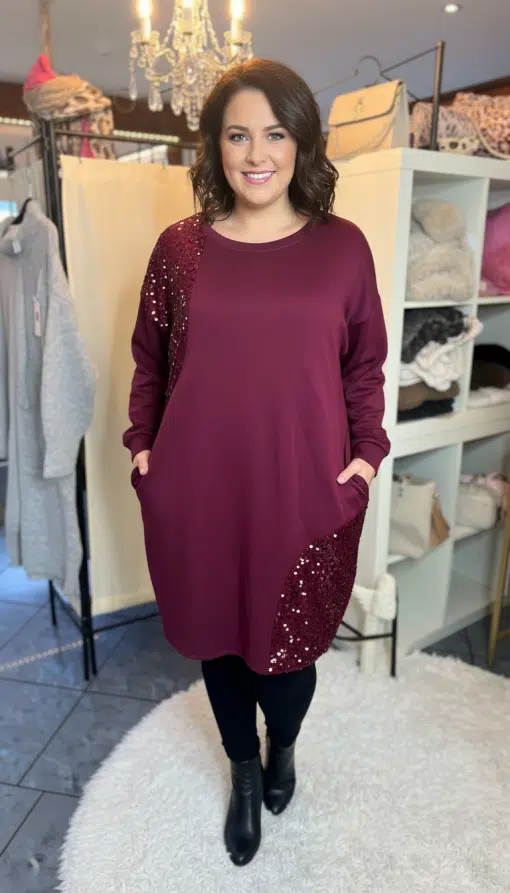 Du trägst das Glam Rouge Kleid mit funkelnden Pailletten, strahlst selbstbewusst und locker - Hände entspannt in den Taschen.