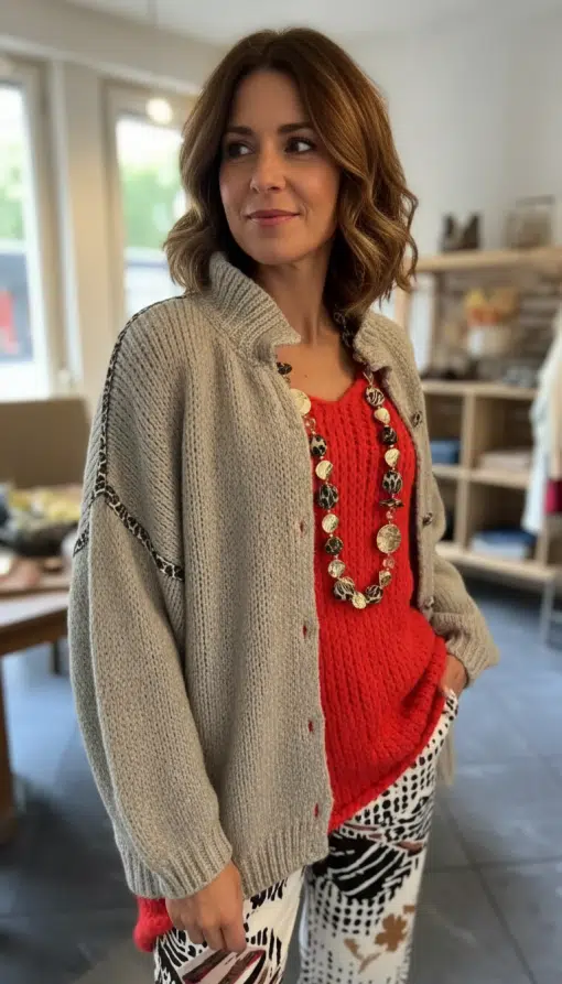 Entdecke deinen Look: Mit der "Luna" Strickjacke XXL, rotem Pullover, gemusterten Hosen und Statement-Kette im Trend-Boutique Flair.