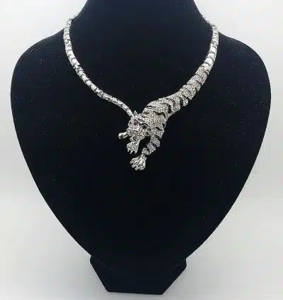 Entdecke das Tiger Royale Collier, kunstvoll wie ein Tiger geformt - dein Highlight auf schwarzem Brustkorb vor weißem Hintergrund.