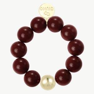 Erlebe das GIUNO-Armband: Kraftvolle bordeauxrote Perlen, ein goldener Akzent und gravierte Scheibe für deinen Signature-Look