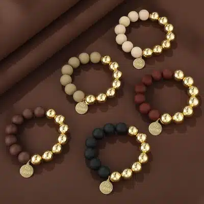 Entdecke deinen Style mit fünf modernen, perlenbesetzten Armbändern und goldenen Akzenten - trendy präsentiert auf braunem Hintergrund.