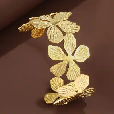 Entdecke dein neues Lieblingsaccessoire: Ein modernes Goldarmband mit auffällig strukturierten Blüten auf braunem Hintergrund.