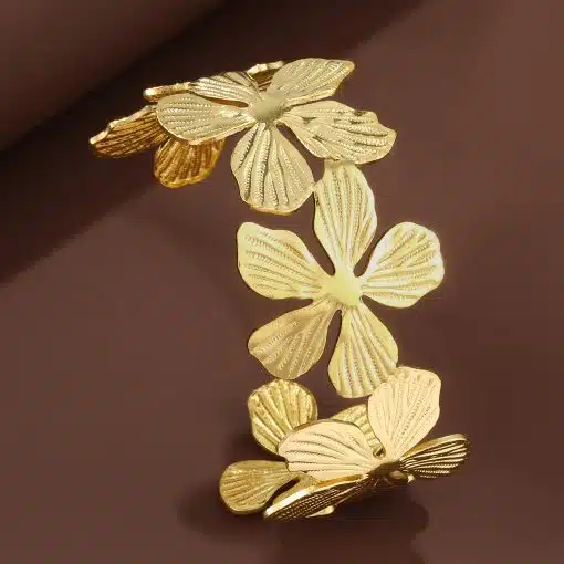 Entdecke dein neues Lieblingsaccessoire: Ein modernes Goldarmband mit auffällig strukturierten Blüten auf braunem Hintergrund.