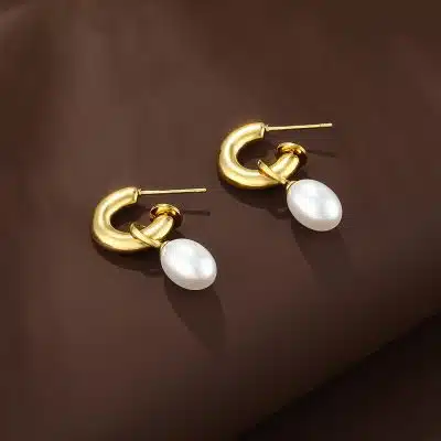 Erlebe den modernen Luxus: Goldene Luxe Curve Drops mit eleganten weißen Ovalanhängern auf edlem Braun - dein neues Style-Highlight.