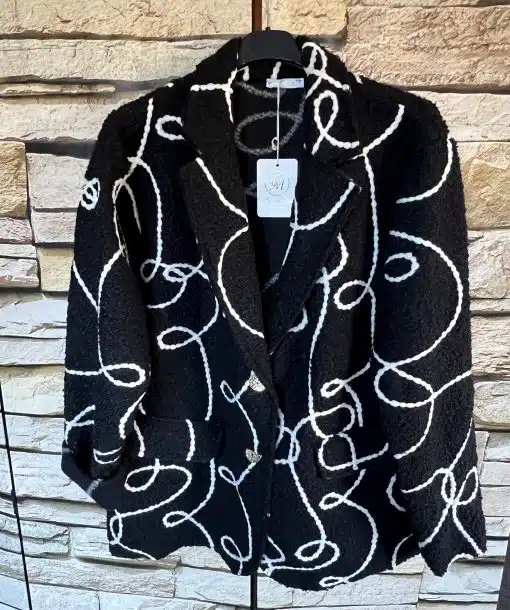 Erlebe den WoolLine Blazer - schwarzer Wollblazer mit markantem weißen Linienmuster, cool inszeniert vor Steinwand.