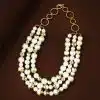 Entdecke dein neues Must-have: Dreireihige Perlen-Goldkette - ein echtes Statement auf braunem, stilvollem Hintergrund.