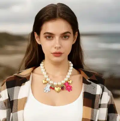 Tragen Sie diese moderne Perlenkette mit Herz- und Handanhängern zum coolen Karohemd und strahlen Sie stilvoll am Strand.