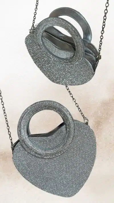 Erlebe die funkelnde Diamant Herz-Clutch - dein silbernes It-Piece mit runden Griffen und stylischen Ketten auf coolem Hintergrund.