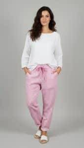 Erlebe den Zauber: Du strahlst in weißem Longsleeve und der zauberhaften Relax Hose mit pinken Mustern vor grauem Hintergrund