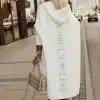Du trägst deinen weißen Simpla Live Cardigan mit "SIMPLY LIVE"-Schriftzug, dazu eine beige Tasche - urban, modern, selbstbewusst.
