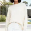 Erlebe pure Leichtigkeit: Du trägst den Pure Ease Pullover in Creme und weißen Hosen - moderne Eleganz vor Garten-Panorama.