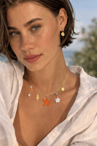 Die goldenen Muschelohrringe von Sand & Meer und die Seestern-Halskette mit Blumencharme verleihen jedem Outfit küstennahe Eleganz, einen lebendigen Stil und einen einzigartigen Reiz.