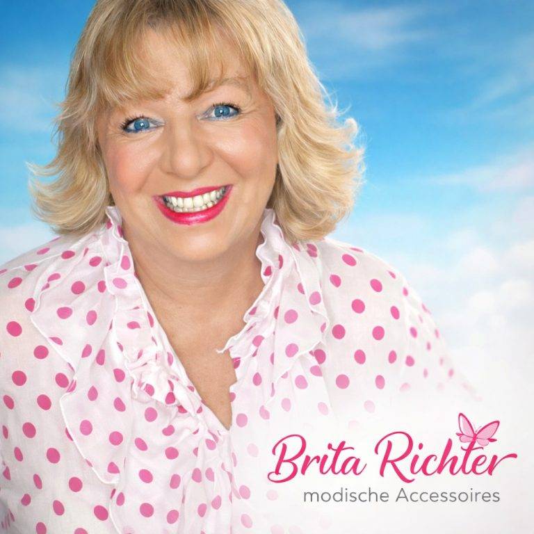 Brita Richter Porträt: Freundliche Frau mit blonden Haaren und blauem Hemd mit rosa Punkten vor blauem Himmel.