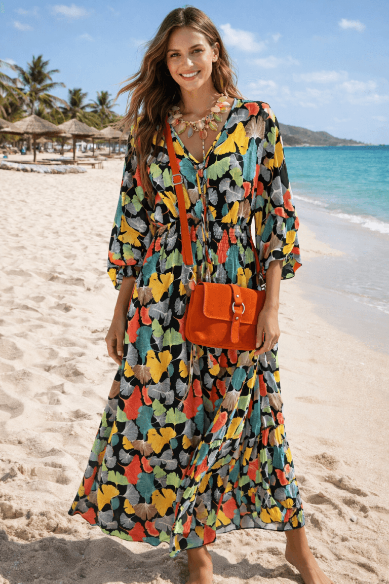 Ginkgo Boho Kleid: Frau am Strand mit farbenfrohem Ginkgo-Kleid und orangefarbener Umhängetasche.