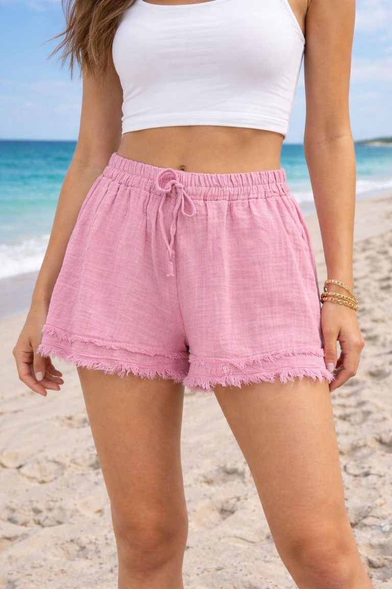 Eine Frau am Sandstrand trägt Cotton Cloud Shorts mit ausgefransten Säumen - atmungsaktiver, modischer Komfort, ideal für die Sommerentspannung.