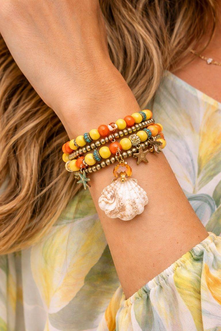 Nahaufnahme von Ocean Wrap-Armbändern in Gelb, Orange und Grün mit Seestern-Anhängern und Muschel-Anhängern; verleiht ein ozeanisches Flair.