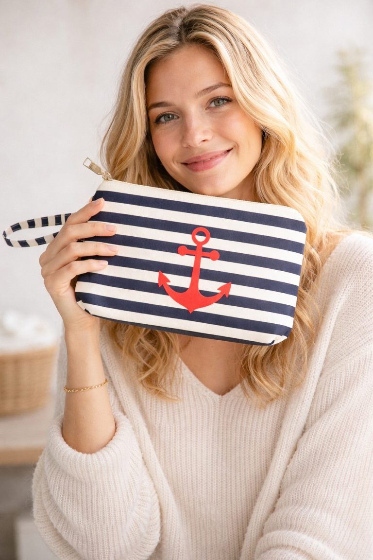 Ahoi Beauty Tasche: Navy and white striped pouch with a red anchor, held by a woman. Stylish, nautical-themed cosmetic bag with handle.