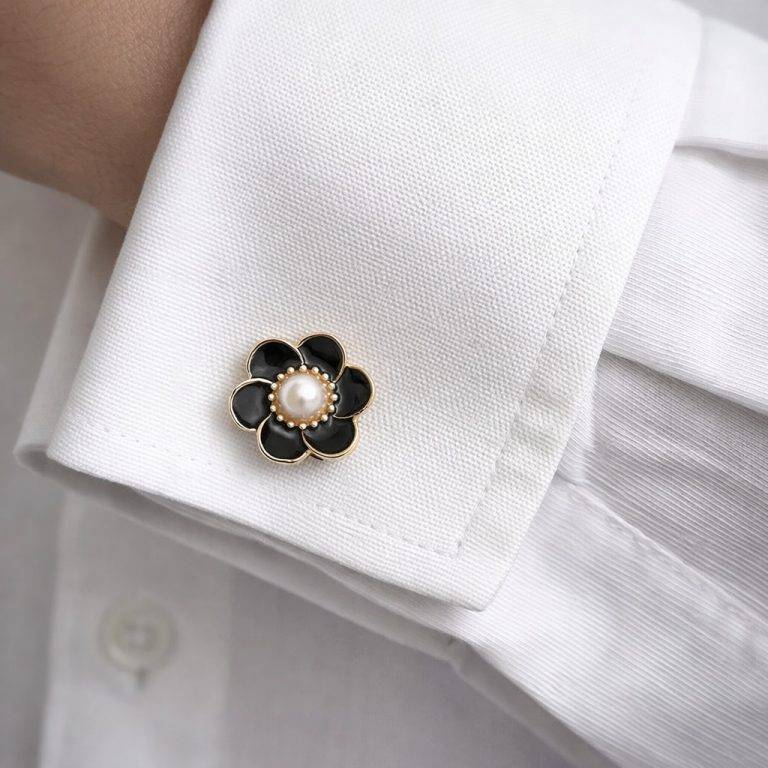 Schwarze Manschettenknöpfe in Blumenform mit Perle auf einem weißen Hemd.