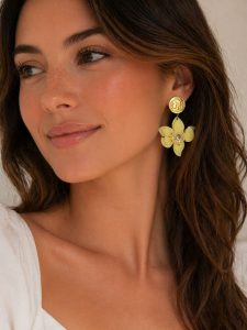Frau modelliert Statement-Ohrringe mit goldenem Münzdesign, gelben Blütenblättern und Strassstein in der Mitte - das verleiht Eleganz und einzigartiges Flair.