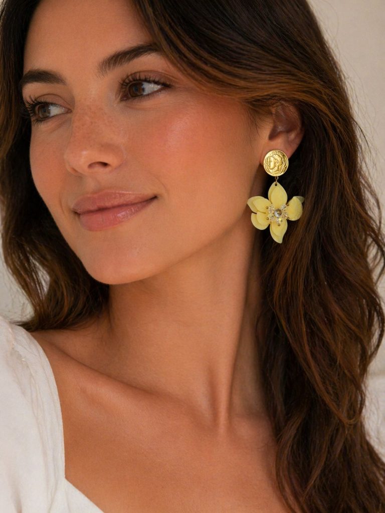 Frau modelliert Statement-Ohrringe mit goldenem Münzdesign, gelben Blütenblättern und Strassstein in der Mitte - das verleiht Eleganz und einzigartiges Flair.