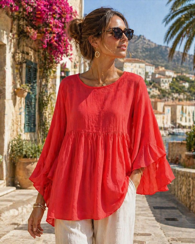 Marisol modelliert die farbenfrohe Marisol Tunikabluse, die luftigen Komfort und Stil bietet. Kombiniert mit einer weißen Hose entsteht ein schicker Sommerlook.