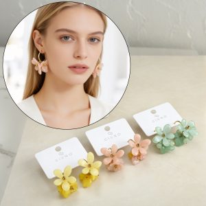 Model mit GIUNO "Soft Petals" Statement-Ohrringen; wählen Sie zwischen Gelb, Pfirsich oder Grün für kräftige Farben und einen einzigartigen floralen Stil.