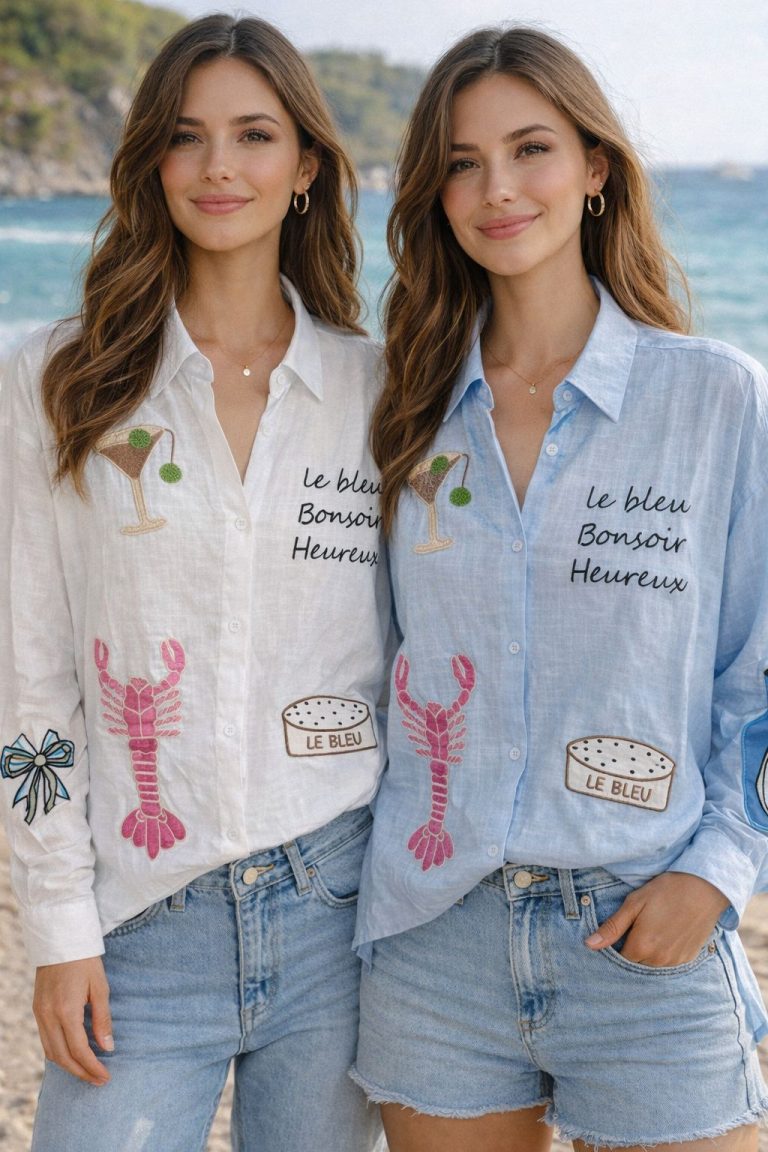 Zwei Frauen am Strand tragen Bon Soir Bluse-Shirts mit lustigen Stickereien, die sich perfekt für einen verspielten Stil am Meer und sommerlichen Komfort eignen.