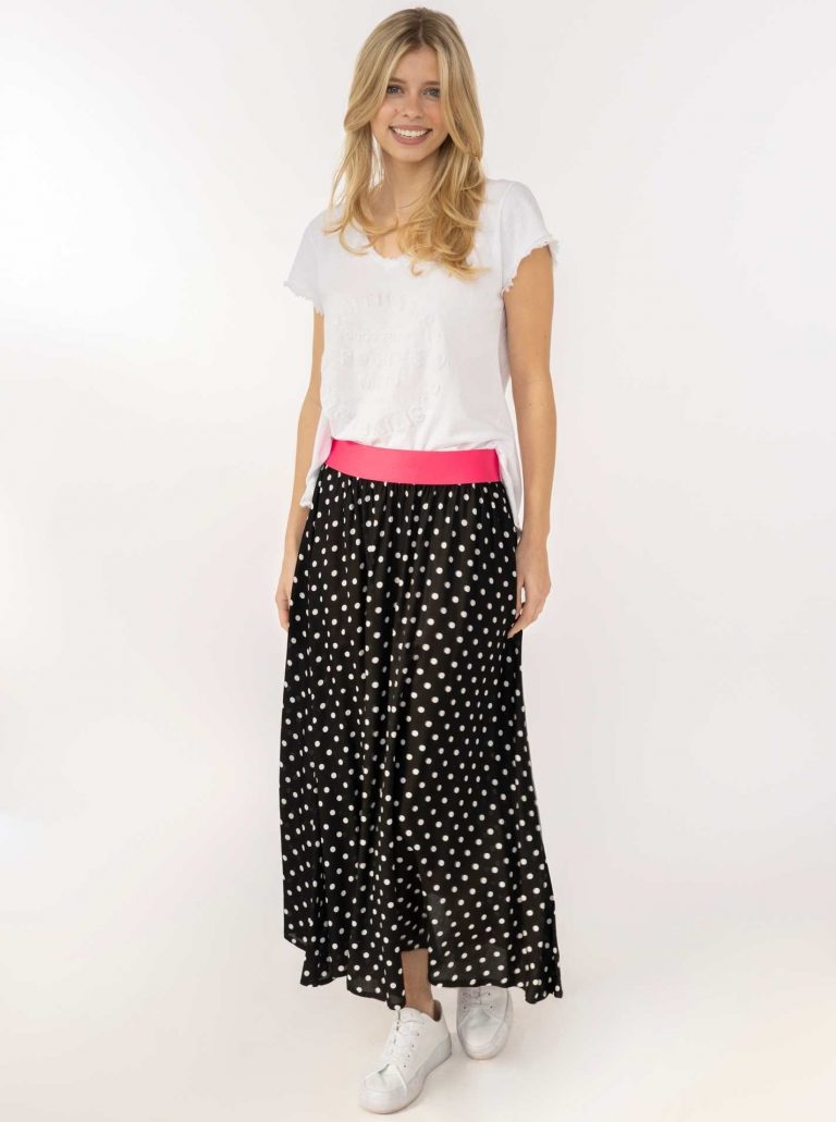Eine Frau modelliert den Dots Allover Rock - schwarzer gepunkteter Maxirock mit rosa Bund. Stylisch, vielseitig, bequem für alle Gelegenheiten.