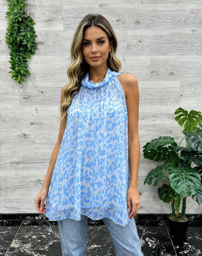 Eine Frau modelliert eine ärmellose, luftige blau-weiße Leo Neck Bluse, die perfekt für sommerlichen Komfort ist und sich leicht mit Jeans kombinieren lässt.