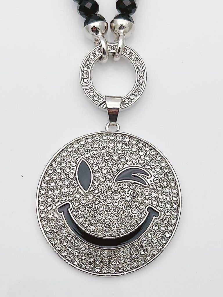 Die Perlenkette „Baby Turtle Anhänger (Kopie)“ besticht durch verspielte schwarze und silberne Perlen sowie einen Smiley-Anhänger mit Strasssteinen, der augenzwinkernd lächelt – für einen verspielten Look.